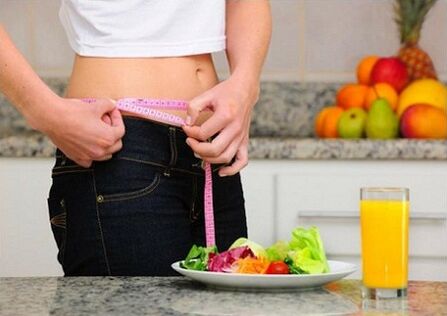 Seorang gadis yang menurunkan berat badan karena diet mengukur ukuran pinggangnya